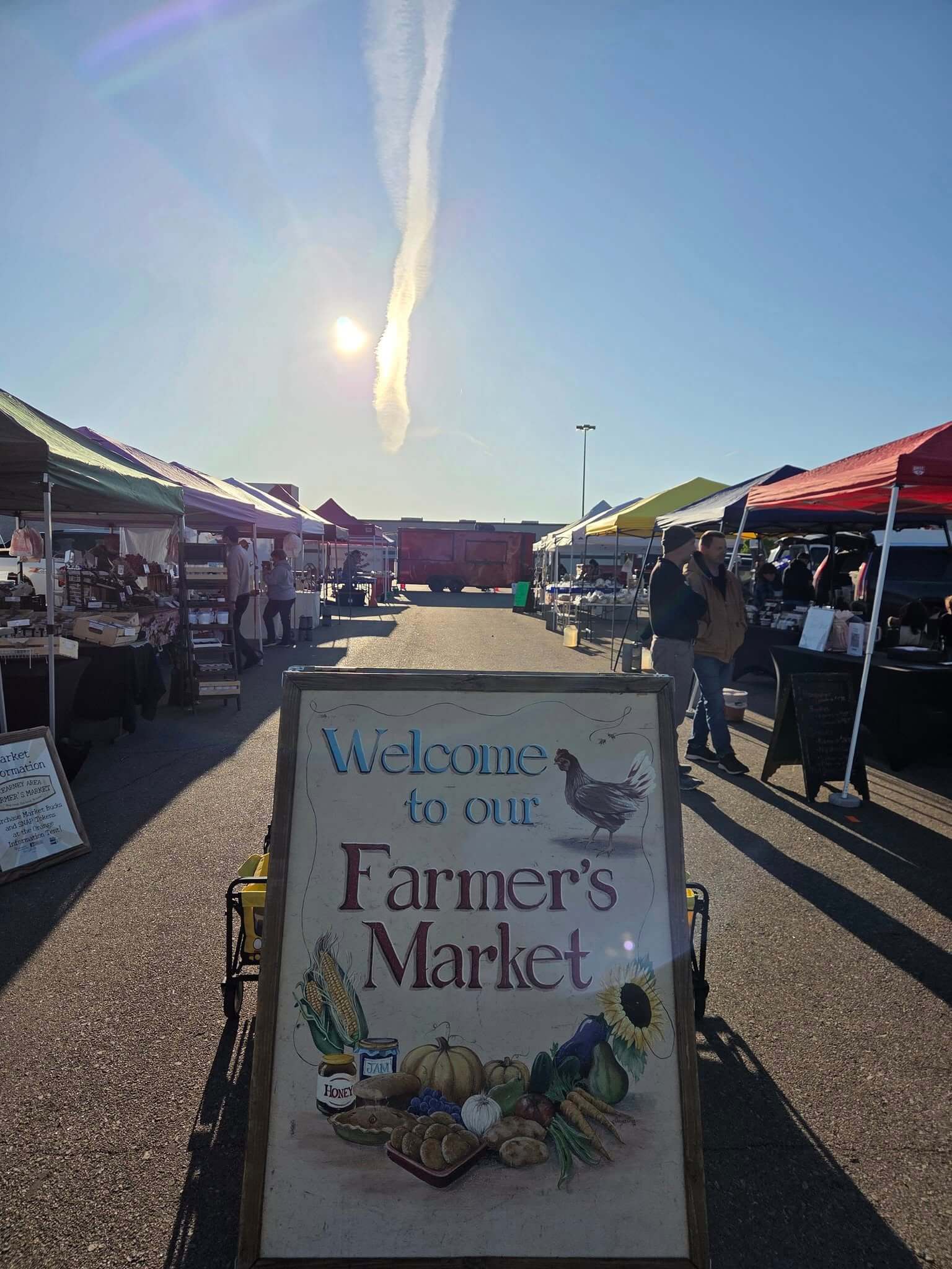 Kearney Area Farmers Market welcome sign with booths behind it